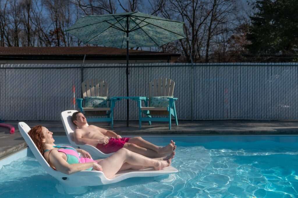 Adults relaxing in a Thursday fiberglass pool after ensuring water safety for kids.