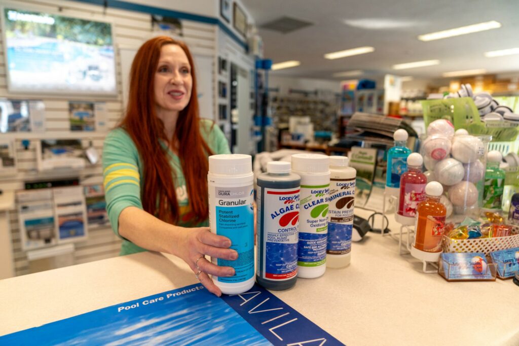 A salesperson pushes pool chemicals over a counter to a customer.