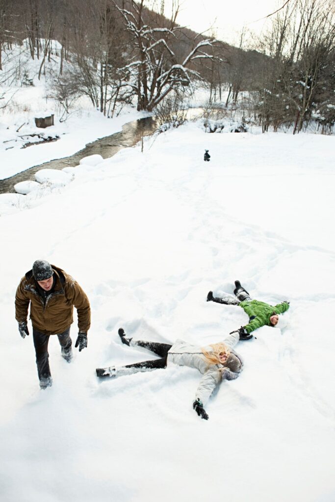 A family making snow angels outside in the winter.